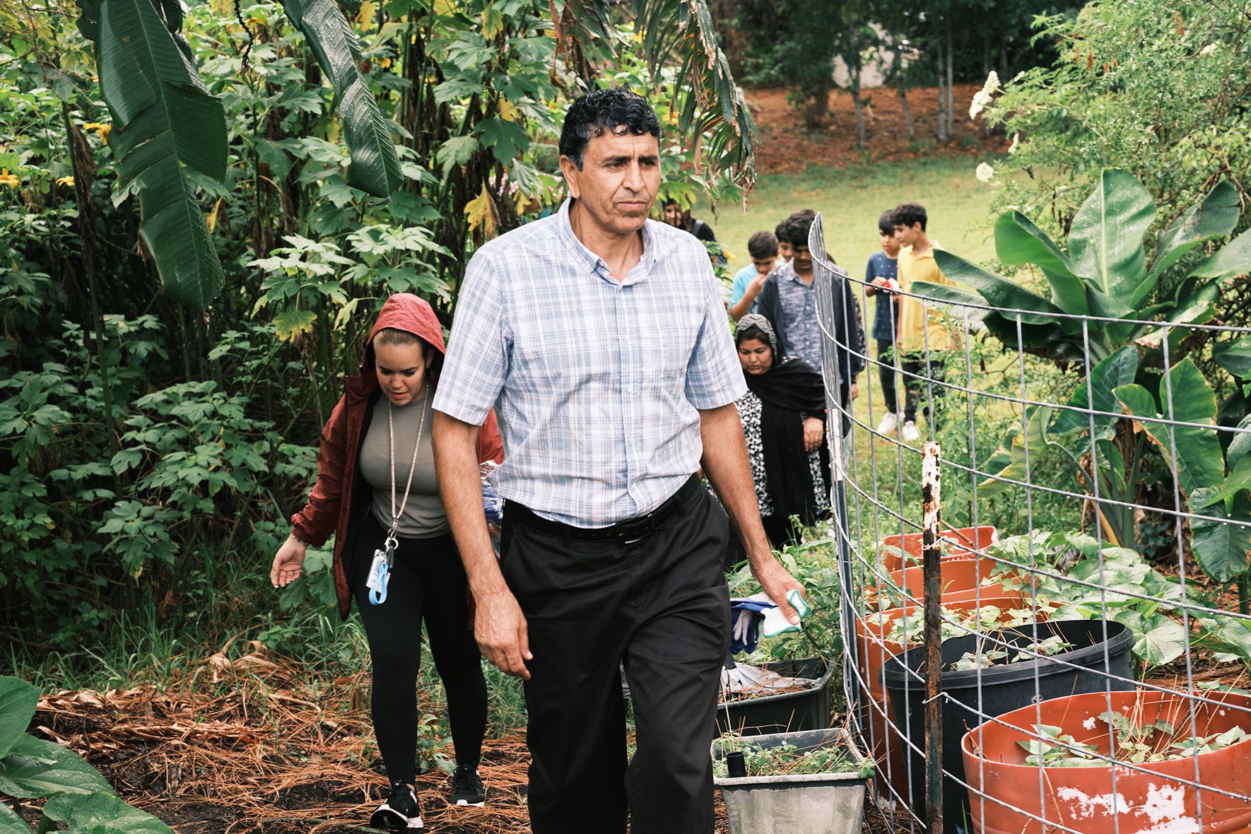 Rahmatullah Hamkar, an Afghan evacuee who was resettled by Gulf Coast JFCS, leads a group of other refugees in clearing land for their community garden on June 1, 2023 at the Gulf Coast JFCS Refugee Garden in Clearwater, Florida. | Community Garden for Refugees Offers Belonging & a Taste of Home | HIAS