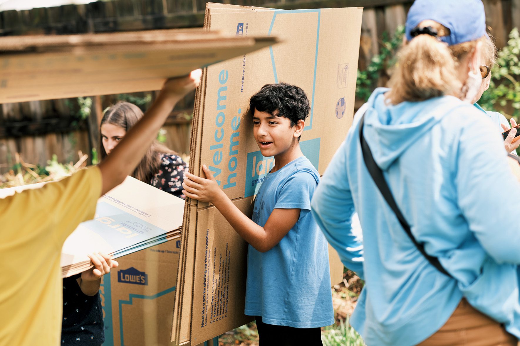 Rahmatullah Hamkar's 9-year-old son, Omar Hamkar, carries cardboard boxes to create a base for the organization's Refugee Garden on June 1, 2023 at the in Clearwater, Florida. | Community Garden for Refugees Offers Belonging & a Taste of Home | HIAS