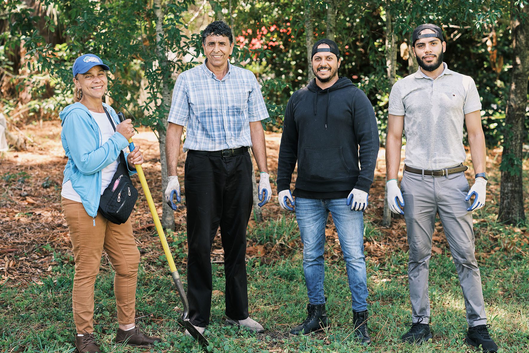 (Left to Right) Sylvia Acevedo, senior director of refugee and employment services at Gulf Coast JFCS; Rahmattulah Hamkar; Abdel Dana Roca, director of refugee integration; and Abdul Rauf Ghayour, refugee career coach; pose for a portrait together a hard day's work in the Refugee Garden. | Community Garden for Refugees Offers Belonging & a Taste of Home | HIAS