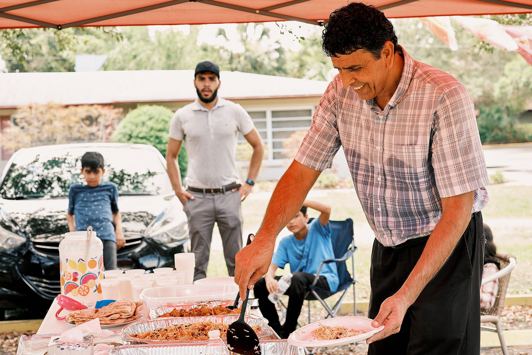 Rahmatullah Hamkar serves himself a plate of food after a hard day's work in the Refugee Garden in Clearwater, Florida on June 1, 2023. Some of the food for the event was made with crops harvested from the garden. | Community Garden for Refugees Offers Belonging & a Taste of Home | HIAS
