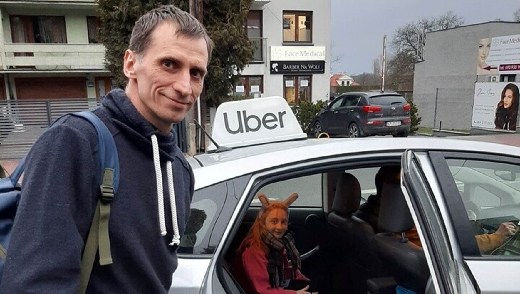 Hombre fuera de un coche Uber, niña dentro de un coche plateado