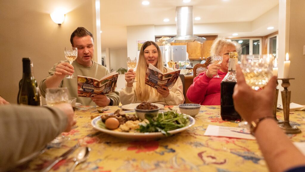 Members of the Levit/Kushnarov family, who fled Ukraine and were resettled in the U.S. by a HIAS Welcome Circle, raise their wine glasses while reading from the Haggadah during a Passover Seder with members of their Welcome Circle in Portland, Oregon.