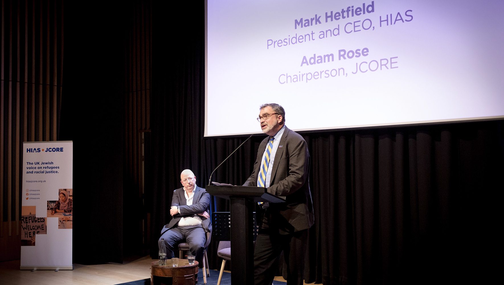 HIAS President and CEO Mark Hetfield welcomes the audience as HIAS+JCORE Chairperson Adam Rose looks on at the JW3 in London, March 28, 2023. (Mike Stone for HIAS+JCORE)
