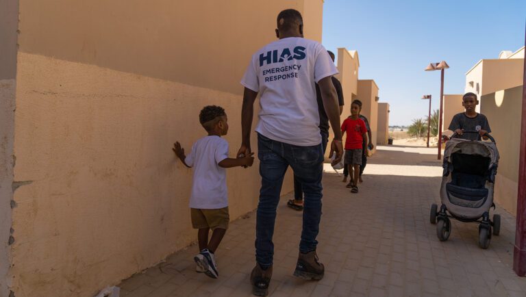 HIAS emergency partnerships coordinator Abdelmonim Haroon, who is himself an asylum-seeker, hold hands with an Eritrean boy displaced during the October 7 attacks.