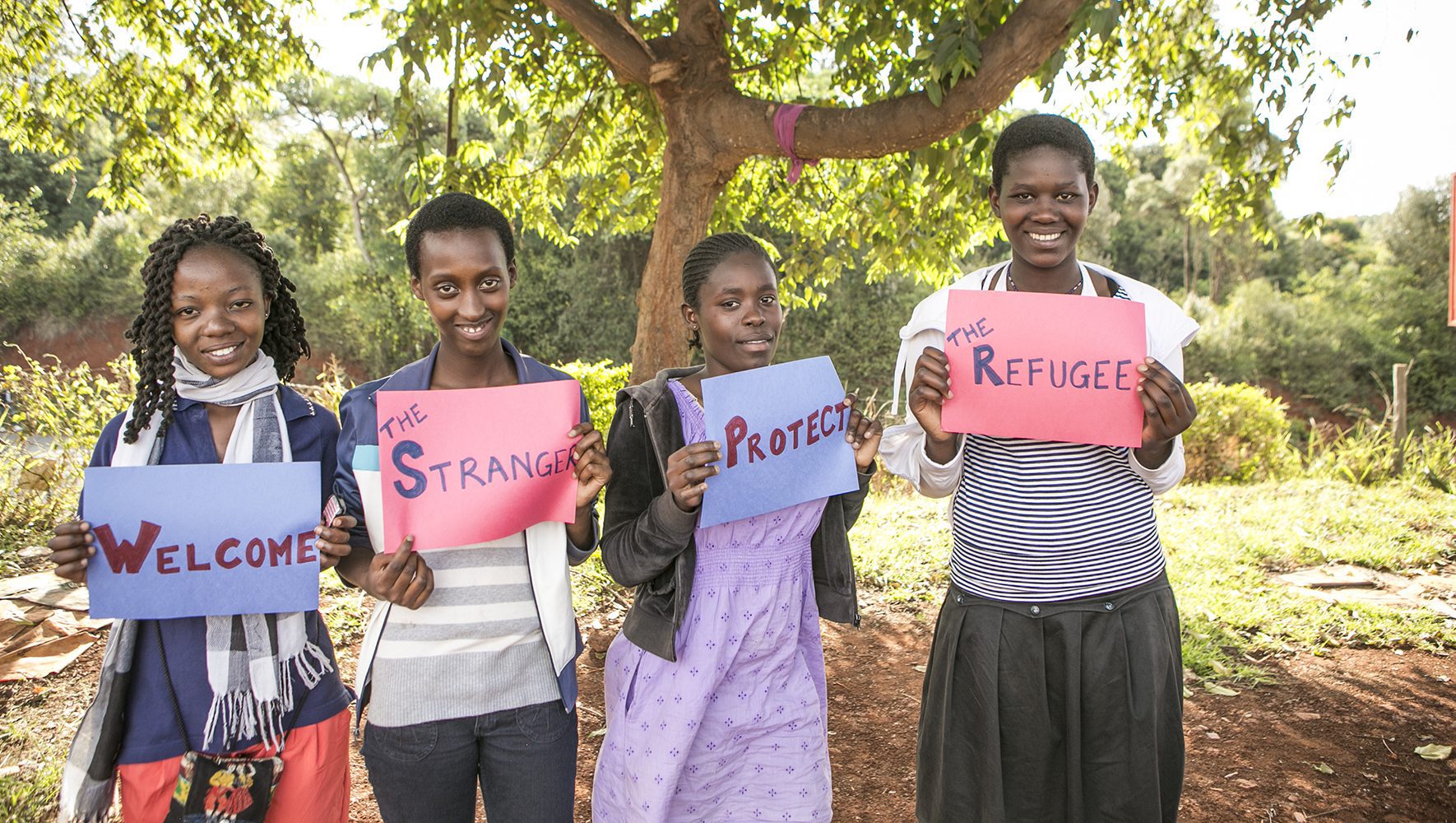 Refugees in foster care and other vulnerable youth carry signs about welcoming the stranger and protecting the refugee during a quarterly play day organized by HIAS staff in Nairobi, Kenya on November 22, 2013. | Congregational Values | Join the HIAS Welcome Campaign | HIAS