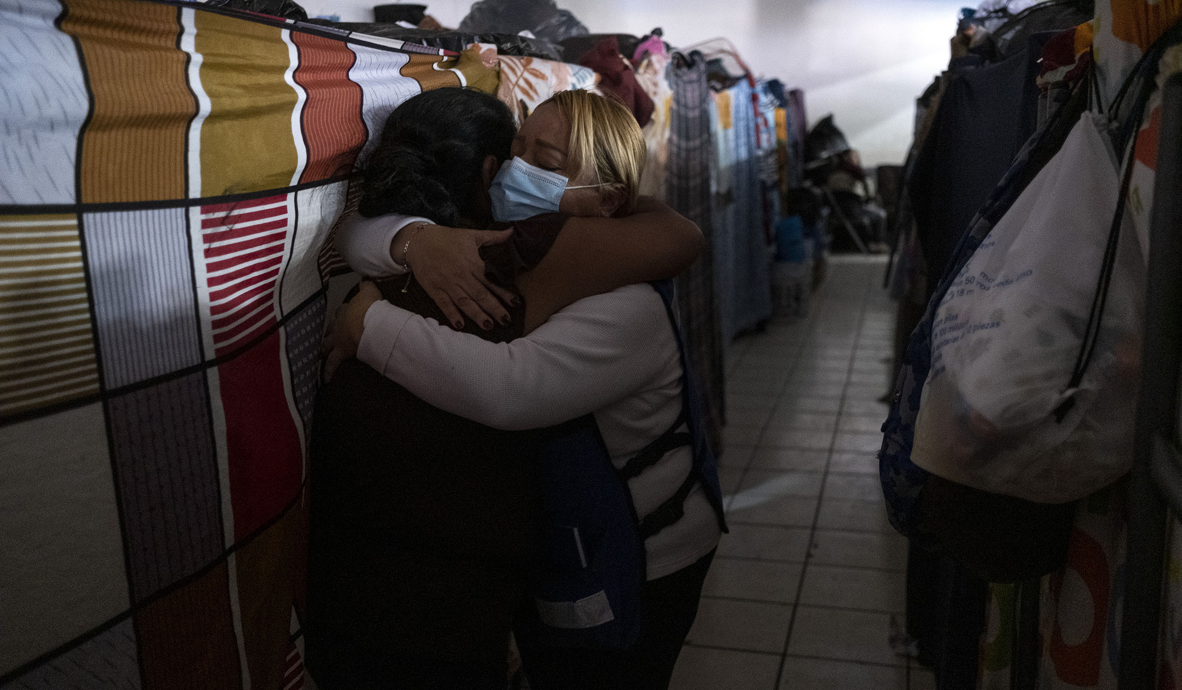A HIAS staffer (right) hugs Juny Araceli Lopez (51), an asylum seeker from Guatemala, at the Embajadores de Jesus migrant shelter in Tijuana, Baja California state, Mexico, on February 17, 2022. Lopez’s 14 year old son, Justin Orlando, was assassinated by mara gangsters while walking with Juny to a grocery store in August 2021. According to Mrs. Lopez, the gangsters killed her son because he refused to work for them. “He never told me the maras were after him because he was trying to protect me, so I couldn’t do anything to save him,” she said. As soon as she recovered from the gun injuries she suffered during the attack, Juny fled Guatemala with her eldest son and family, heading for the United States. She and her family arrived in Tijuana on December 2021, where now they are stranded until US migration authorities resume asylum processes. (Guillermo Arias for HIAS)
