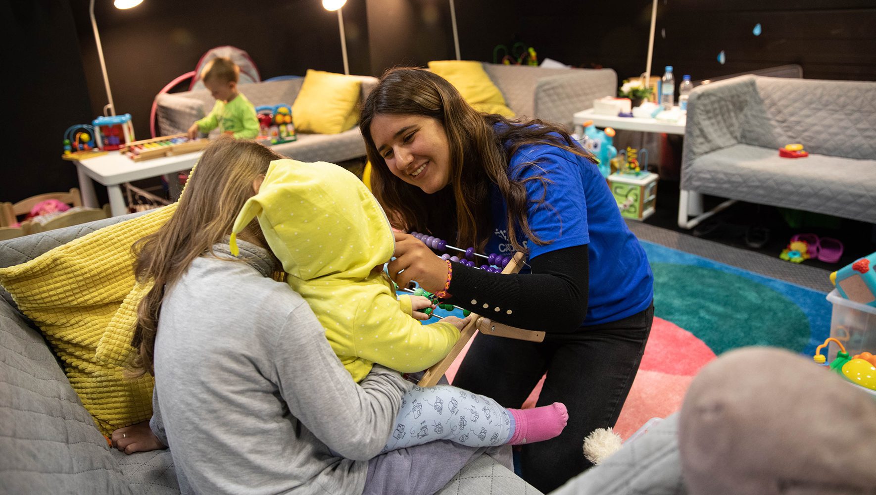Cadena volunteer Victoria Zyman plays with children displaced by the war in Ukraine at a temporary housing center in Nadaryzn, Poland. | Community volunteer with refugees | HIAS