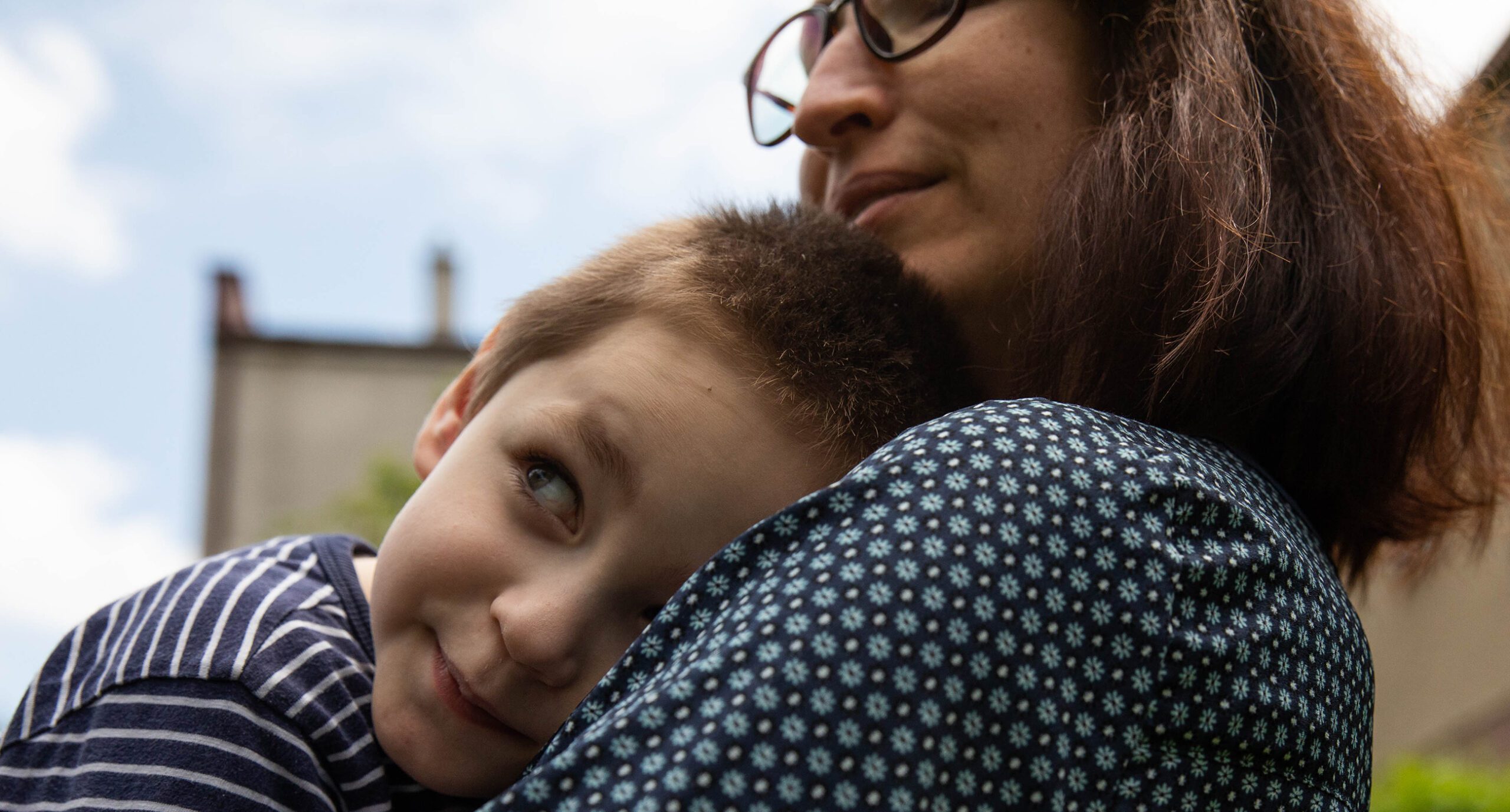 Ilia Ryzka, who has autism and cerebral palsy, hugs his mother, Zoia, in the yard of the L'Arche house where his family stays with other refugees from Ukraine on May 30, 2022 in Wieliczka, Poland. (Betsy Joles for HIAS)
