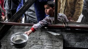 A boy holds out an empty pot as he waits with other displaced Palestinians queueing for meals provided by a charity organisation ahead of the fast-breaking "iftar" meal during the Muslim holy month of Ramadan, in Rafah in the southern Gaza Strip on March 16, 2024, amid the ongoing conflict in the Palestinian territory between Israel and the militant group Hamas.