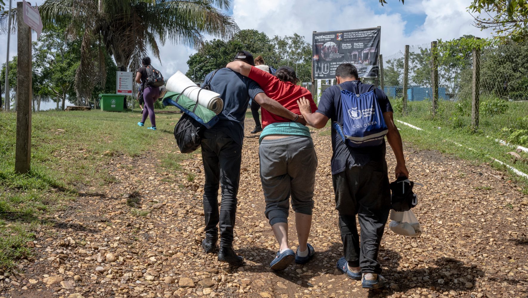 Two migrants help a limping woman.
