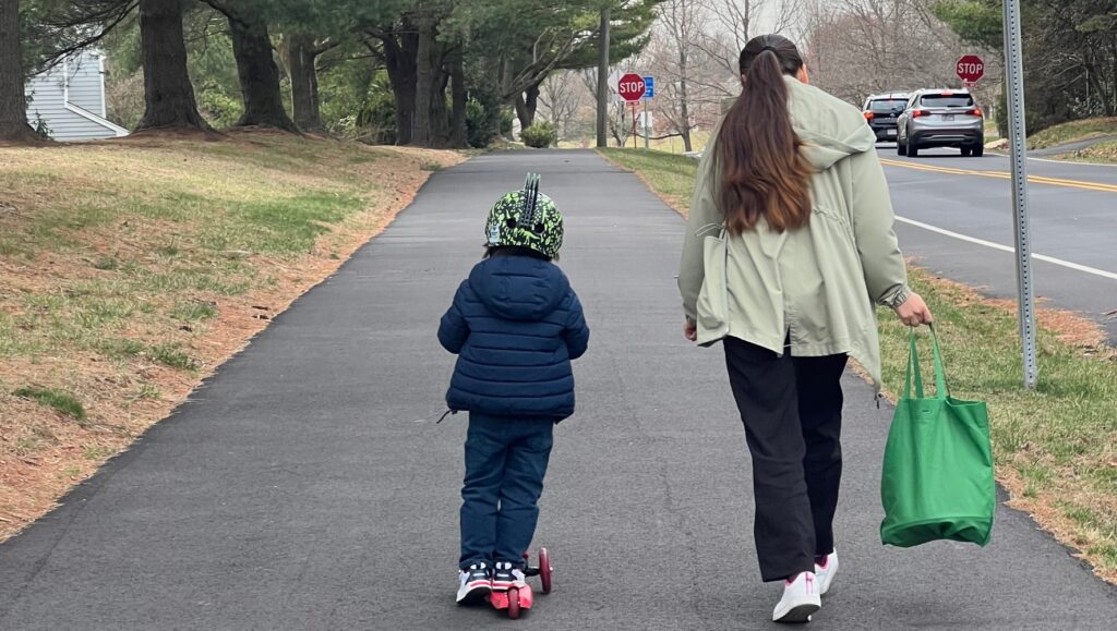 A woman and small child walk down a street.