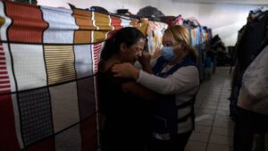 A woman comforts another woman at a shelter.