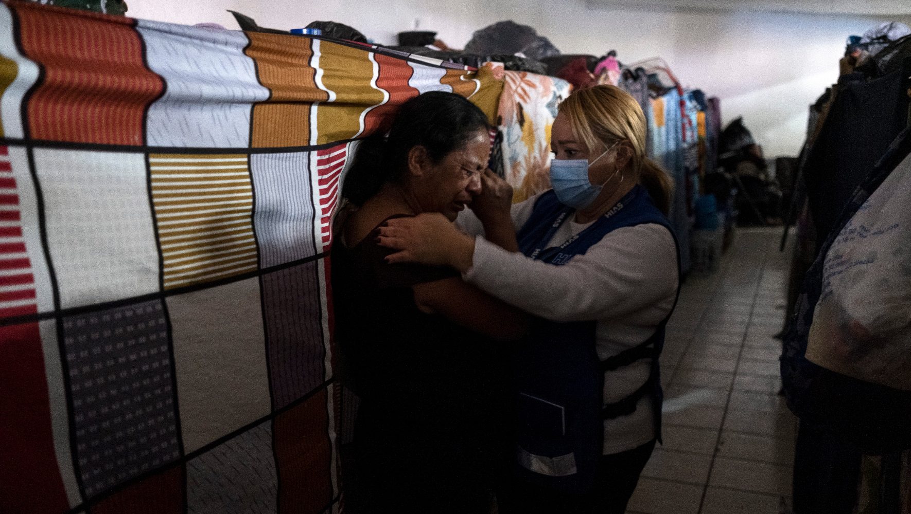 A woman comforts another woman at a shelter.