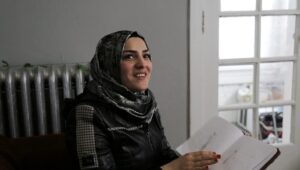 Alaa, a Syrian refugee supported by community sponsorship, shows drawings by her daughter in their Chicago home in 2025. (Lindsay Kagalis/HIAS)