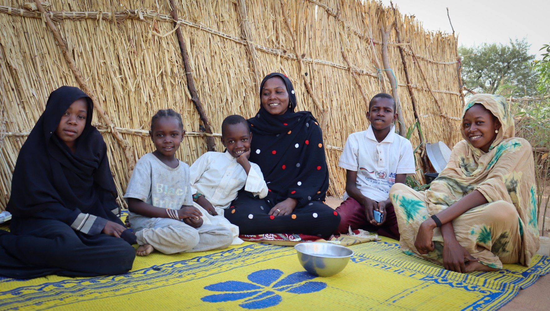 Souad (black dress), a Sudanese refugee who fled the civil war with her children, participates in HIAS Chad activities that provide mental health care, economic assistance, and protection services in the Farchana refugee camp in eastern Chad in June 2026 (Saam Kouakaine for HIAS).