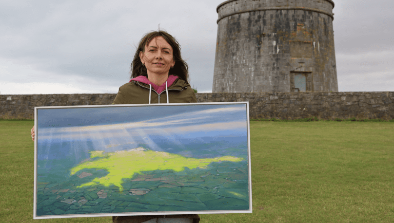 Laura Medvedieva holds up her first oil painting of Ireland, with rays of sun shining down on it, near her home in North County Dublin, August 26, 2022. | Welcome Circles Europe | HIAS
