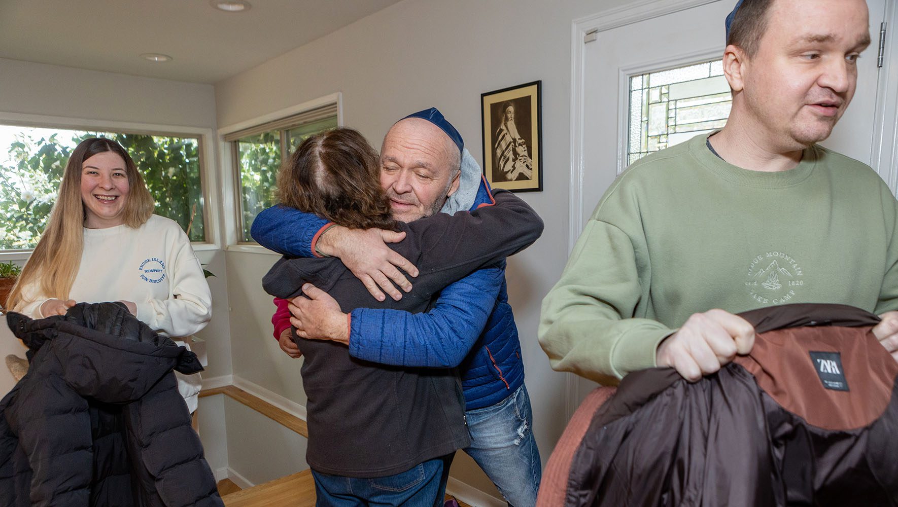 Oleksandr Kushnarov, center, embraces Sara Safdie, as the family arrives at Safdie's home for the Passover Seder. At left is Kushnarov's daughter-in-law, Daria Levit, and at right, his son Eduard Levit. | In Time for Passover, Ukrainians Find Jewish Community in U.S. | HIAS