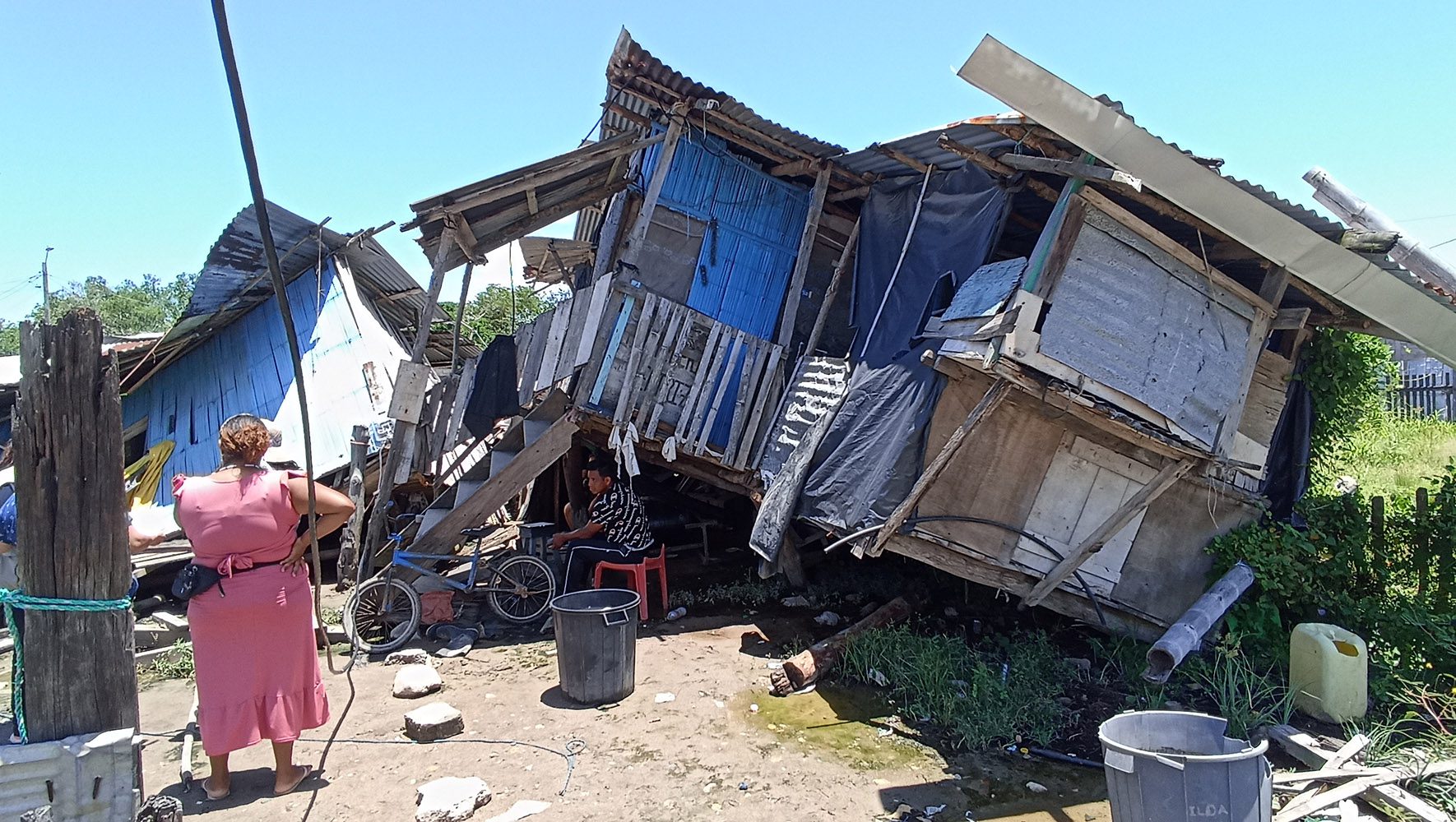 woman stands in front of destroyed house