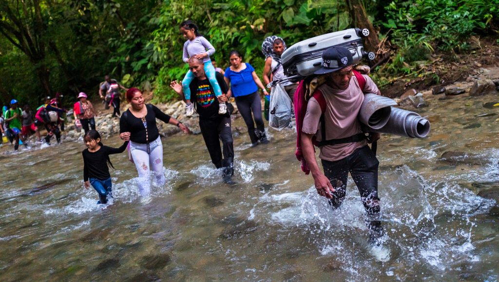 Migrants walk through a river in the inhospitable rainforest of the Darién Gap, Colombia, November 20, 2022. | Center for Refugee Policy } HIAS Center for Refugee Policy | HIAS