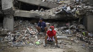 Residents sit amid the rubble of a residential building that collapsed following the two powerful earthquakes on June 24 earthquakes, in Caraballeda, Venezuela, on July 20, 2026. (Federico PARRA/AFP via Getty Images)