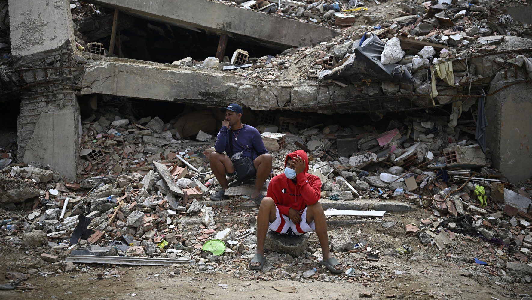 Residents sit amid the rubble of a residential building that collapsed following the two powerful earthquakes on June 24 earthquakes, in Caraballeda, Venezuela, on July 20, 2026. (Federico PARRA/AFP via Getty Images)