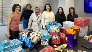 HIAS staff and volunteers pose with a pile of toys they have finished wrapping. The gifts were donated as part of a holiday toy drive for HIAS legal clients and their families at HIAS’ headquarters in Silver Spring, Maryland on December 11, 2023.