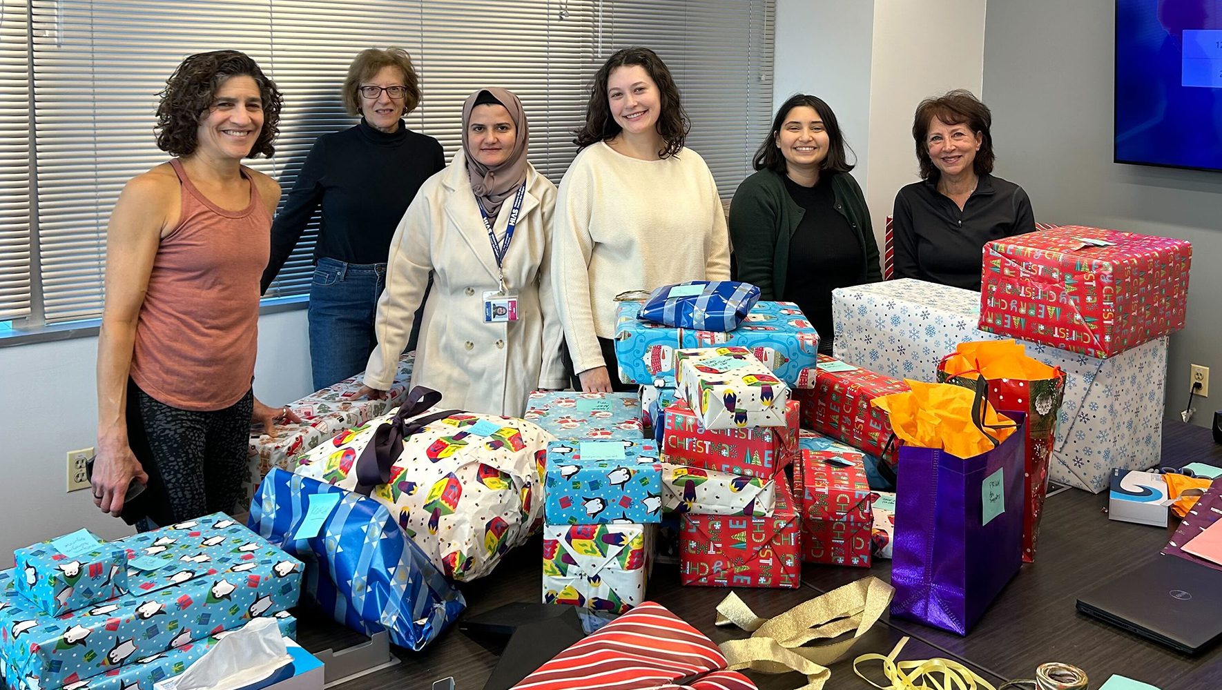 HIAS staff and volunteers pose with a pile of toys they have finished wrapping. The gifts were donated as part of a holiday toy drive for HIAS legal clients and their families at HIAS’ headquarters in Silver Spring, Maryland on December 11, 2023. | Holiday Toy Drive Brings Joy to Asylum Seekers | HIAS