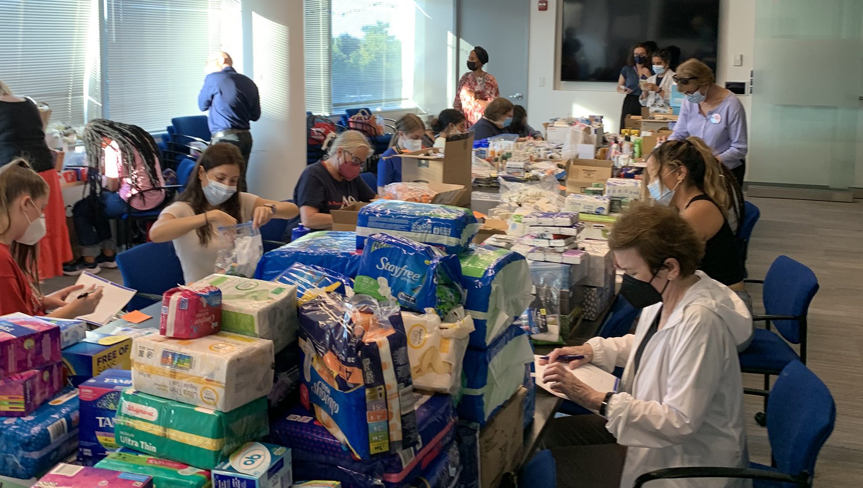 Voluntarios sentados alrededor de una mesa empaquetando kits de dignidad para solicitantes de asilo recién llegados a la sede de HIAS. | Cinco formas de acoger a los refugiados en EE.UU. | HIAS