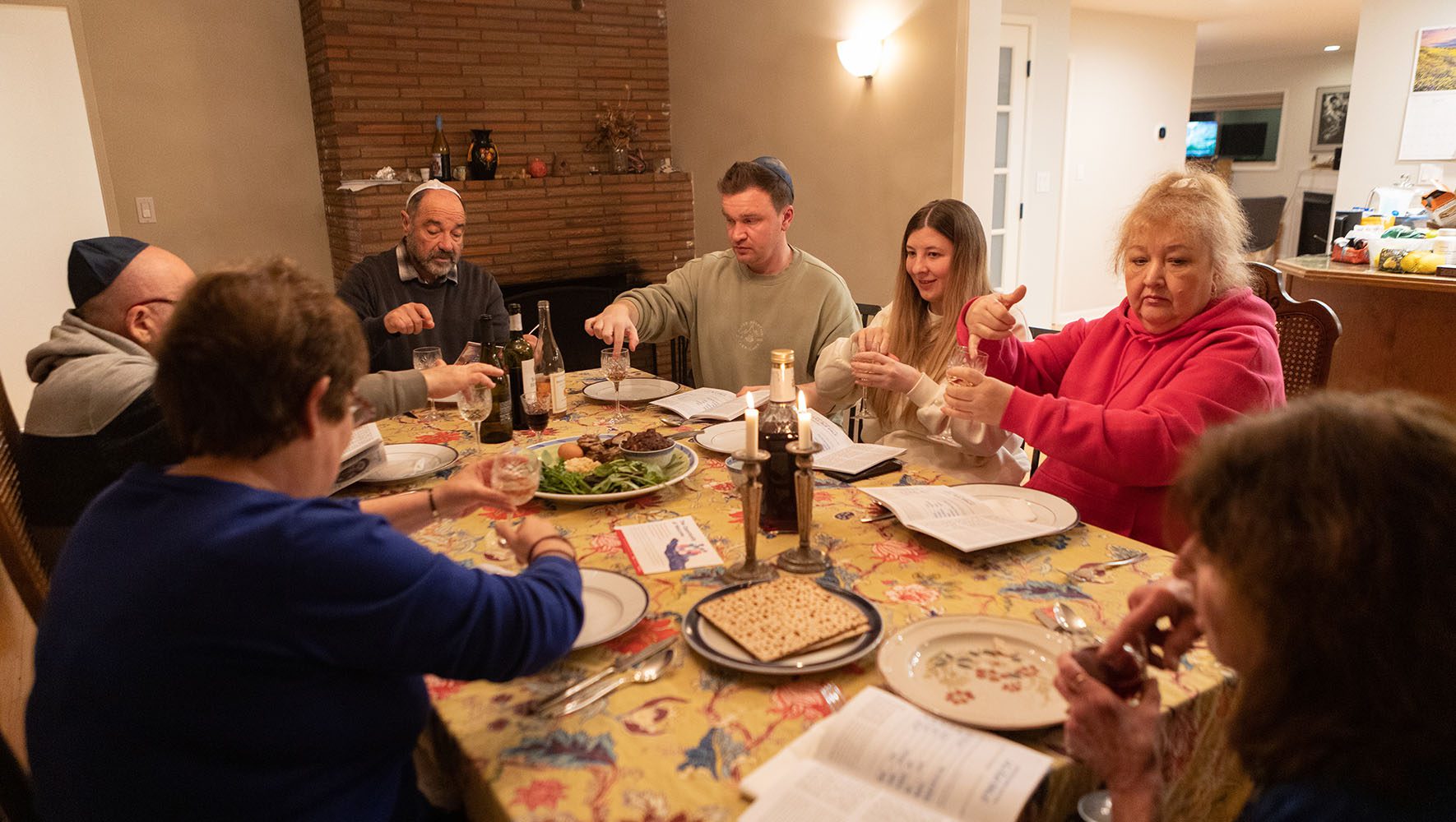 La familia Levit/Kushnarov asiste al seder. Sara Safdie, abajo a la derecha, explica las diez plagas mientras todos extraen una gota de vino de sus copas en conmemoración de cada plaga. | A tiempo para Pésaj, ucranianos encuentran comunidad judía en EE.UU. | HIAS