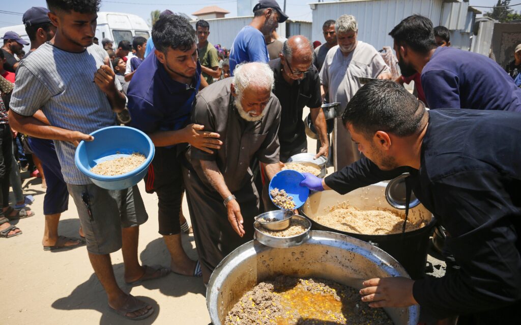 people standing around vat of food