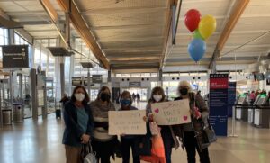 gente en el aeropuerto con carteles de bienvenida y globos