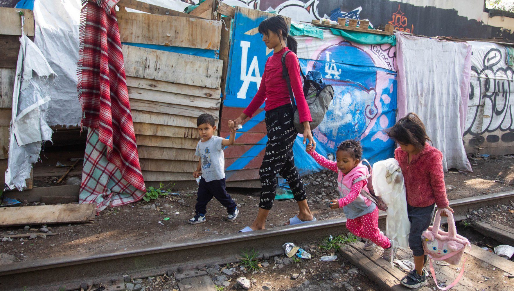 A woman from Venezuela leaves her makeshift shelter to take her children to school, in Mexico City, Mexico on July 3, 2025. Due to changes in U.S. immigration policies, asylum seekers are stranded in Mexico, with many now aiming to return to their home countries while others seek asylum in Mexico. (Daniel Cardenas/Anadolu via Getty Images)