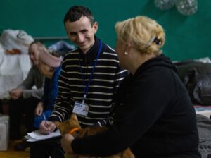 Un trabajador de HIAS Ucrania se sienta con un residente en un refugio de Lviv, Ucrania.